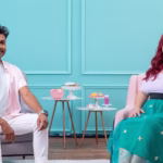 Dos expertos en repostería sentados en un estudio de color pastel, rodeados de pequeñas mesas con galletas decoradas y tazas. El hombre viste camisa rosa y pantalón blanco, y la mujer lleva una blusa blanca y falda verde con estrellas. - Recetas Chidas
