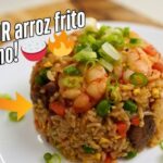 Montículo de arroz frito cubano con jamón, camarones y cebollín picado sobre un plato blanco. La imagen tiene texto que dice "¡El MEJOR arroz frito cubano!" y emojis decorativos. - Recetas Chidas