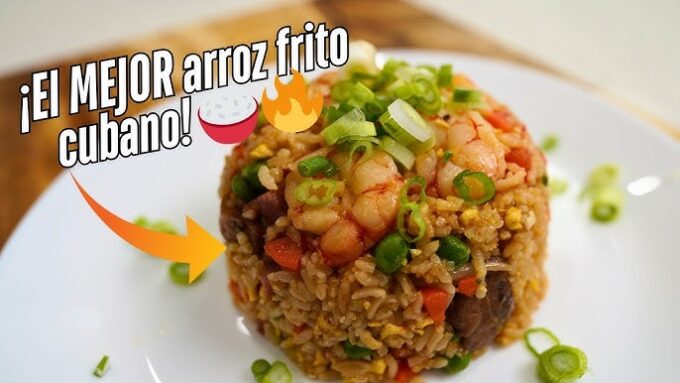 Montículo de arroz frito cubano con jamón, camarones y cebollín picado sobre un plato blanco. La imagen tiene texto que dice "¡El MEJOR arroz frito cubano!" y emojis decorativos.