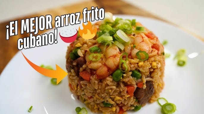 Montículo de arroz frito cubano con jamón, camarones y cebollín picado sobre un plato blanco. La imagen tiene texto que dice "¡El MEJOR arroz frito cubano!" y emojis decorativos.