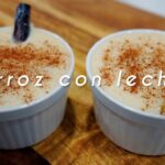 Dos ramequines con arroz con leche cremoso espolvoreado con canela; uno de ellos tiene una rama de canela. Sobre la imagen aparece el texto "Arroz con leche". - Recetas Chidas
