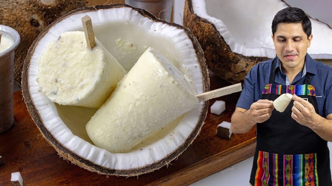 Paletas de helado de coco artesanales servidas dentro de cáscaras de coco, con un hombre sosteniendo y probando una de ellas. - Recetas Chidas