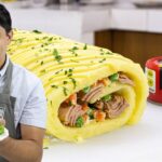 Cocinero con delantal sosteniendo un plato de ensalada junto a un rollo de puré de papa relleno de atún y verduras, con una lata de atún marca Isabel en el fondo. - Recetas Chidas