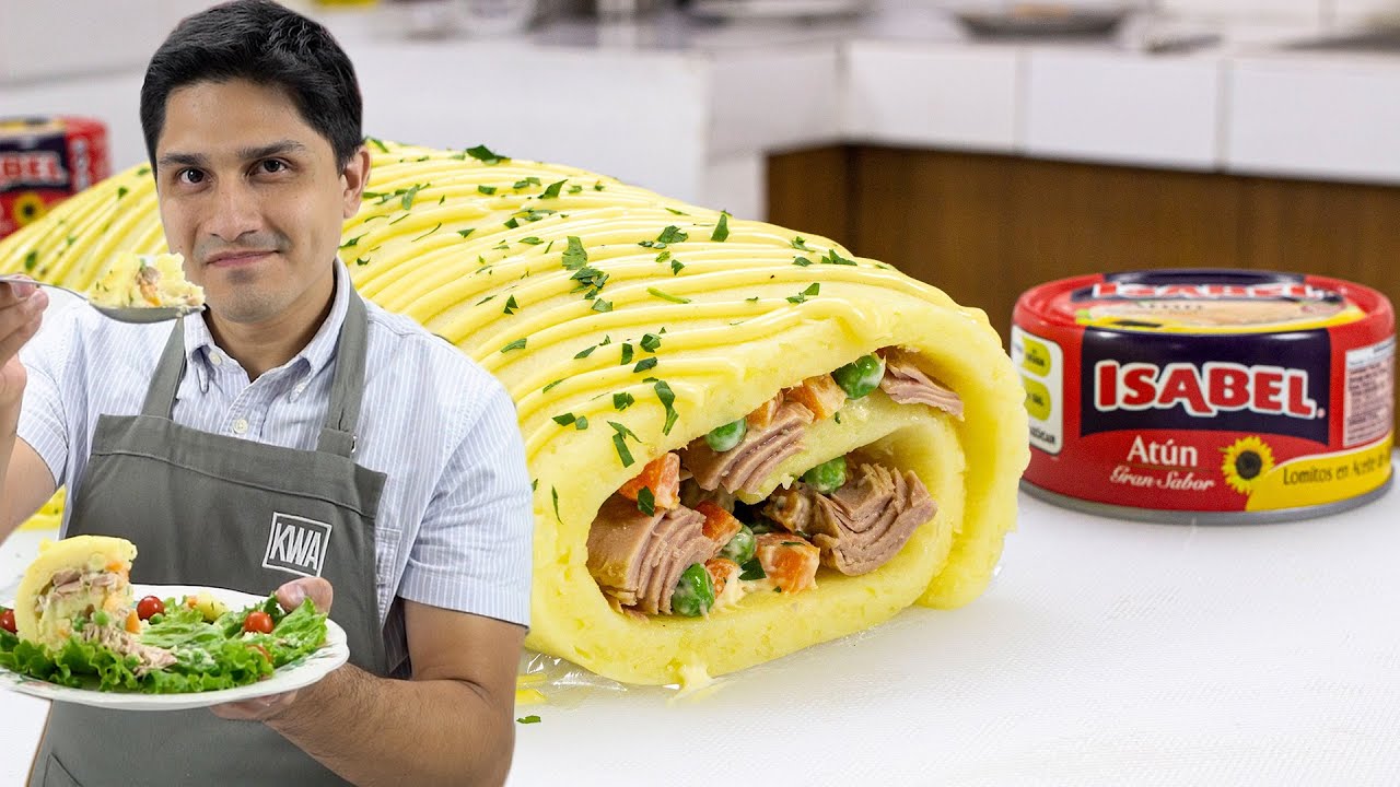Cocinero con delantal sosteniendo un plato de ensalada junto a un rollo de puré de papa relleno de atún y verduras, con una lata de atún marca Isabel en el fondo.