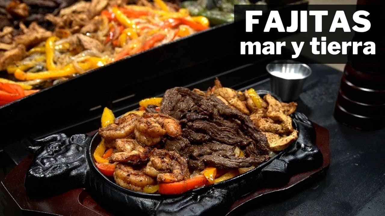 Plato caliente de fajitas mar y tierra con carne, camarones y pimientos de colores servidos en una sartén de hierro sobre una tabla, con texto 'FAJITAS mar y tierra' en blanco.